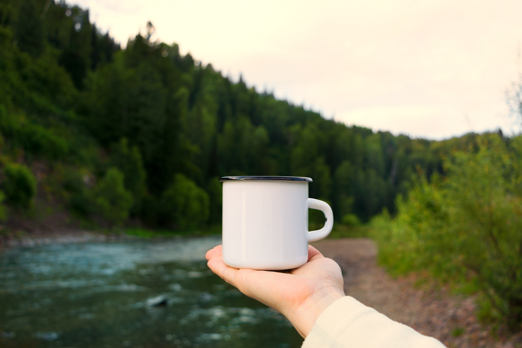 Woman holding enamel mug with riverside view